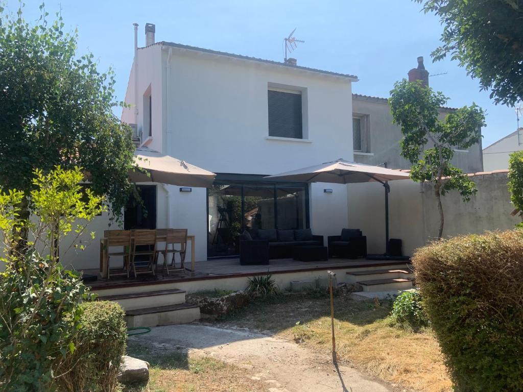 une maison blanche avec une table et un parasol dans l'établissement Villa au calme dans un écrin de verdure, à Aytré