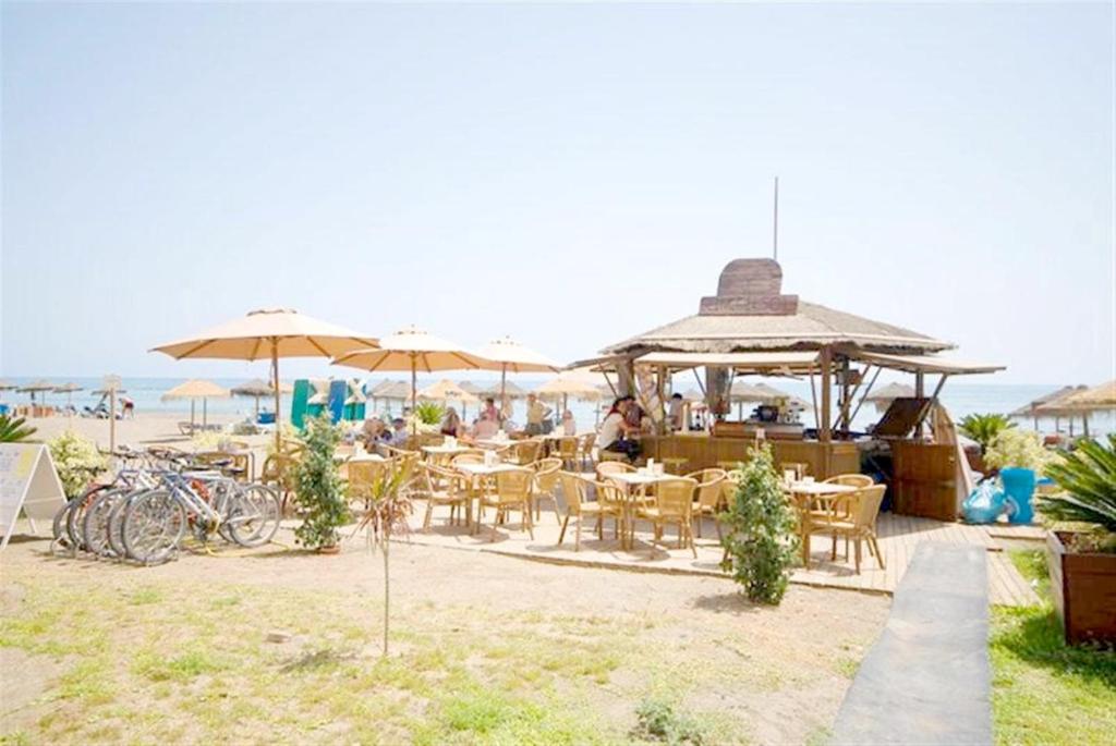 a restaurant with tables and chairs and umbrellas on the beach at Rincón Sol in Rincón de la Victoria