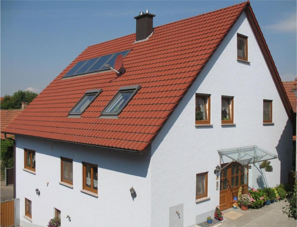 una casa blanca con techo naranja en Ferienwohnung Pfrang en Michelau