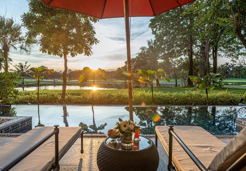 uma mesa com um guarda-chuva ao lado de uma piscina em Summit Windmill Golf Suite Hotel at Suvarnabhumi em Bangna