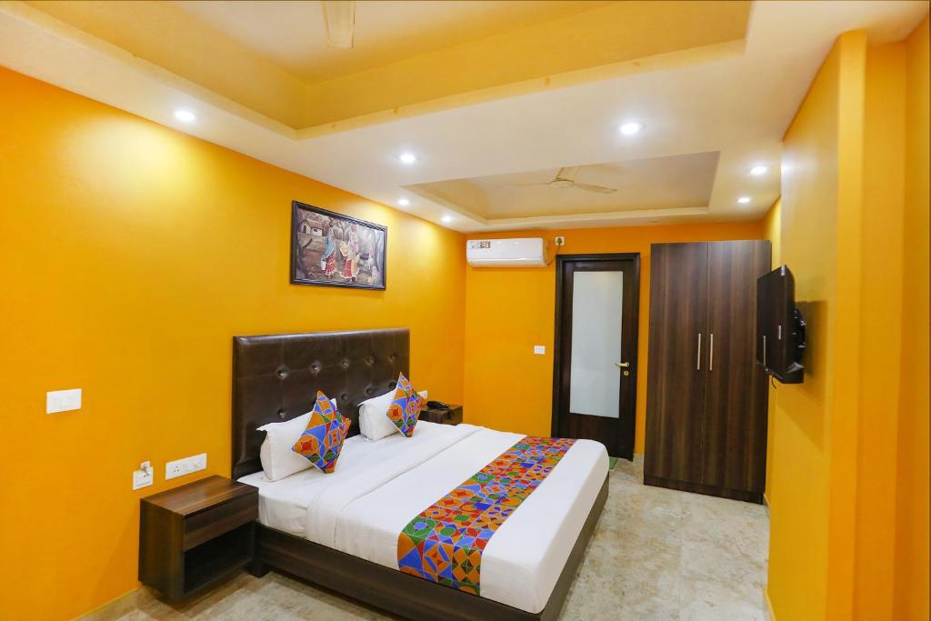 FabExpress Taj Home Stay في نيودلهي: غرفة نوم بسرير كبير وبجدران صفراء
