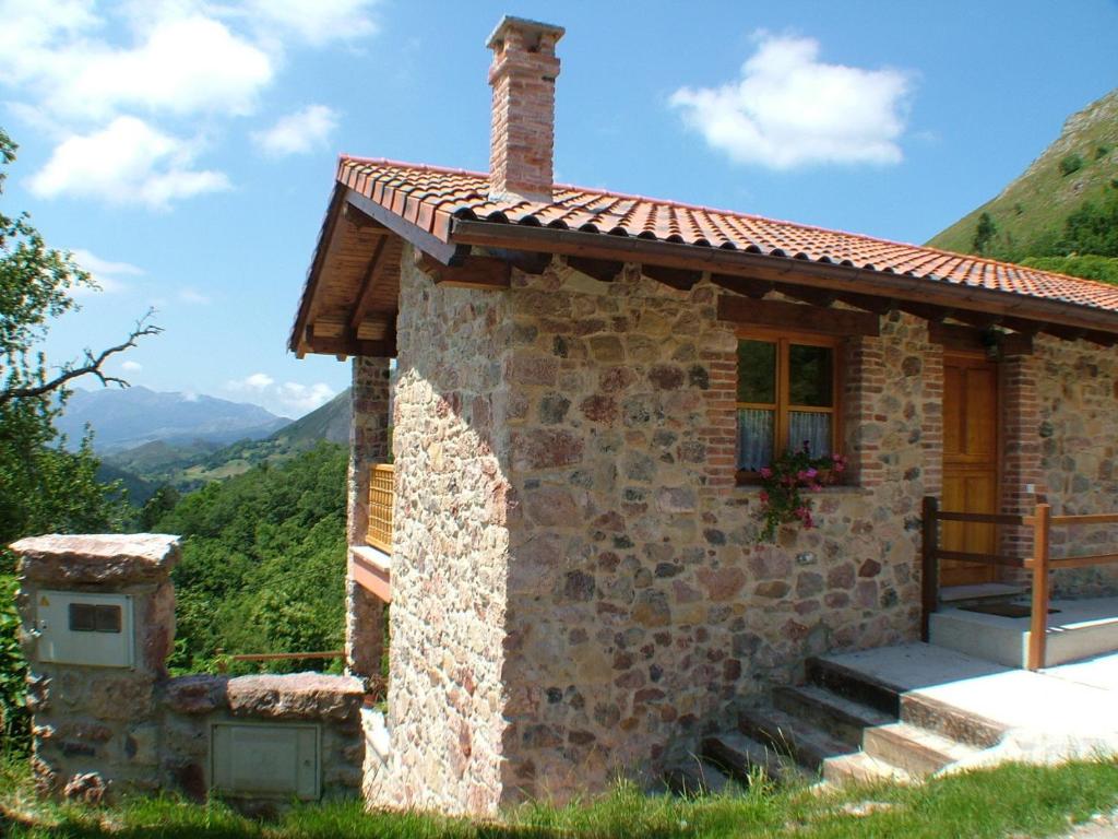 mały kamienny dom z oknem i góry w tle w obiekcie Apartamentos Rurales Vista del Sueve w mieście Tresano