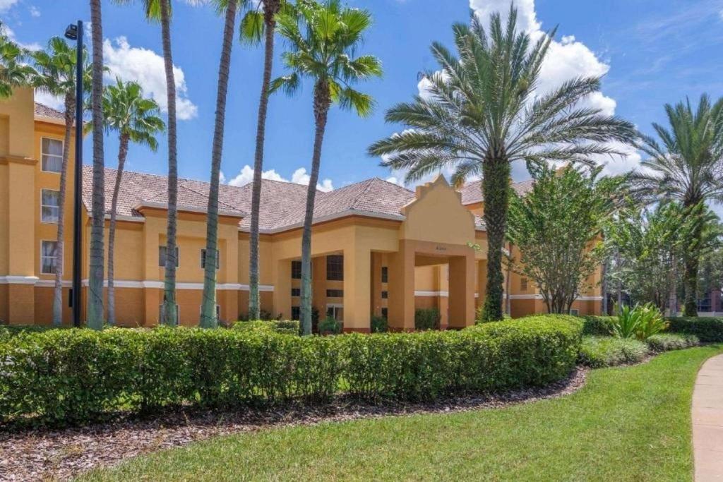 um edifício amarelo com palmeiras em frente em SureStay Plus by Best Western Orlando Lake Buena Vista em Orlando