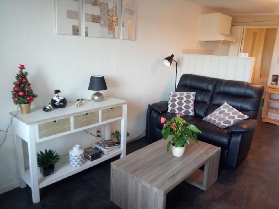 uma sala de estar com uma cadeira de couro preta e uma mesa de centro em Maison Raquet em Jalhay
