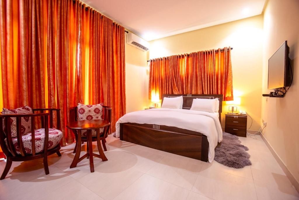 a bedroom with a bed and a table and a chair at Rushmore - Paradise Room in Lagos