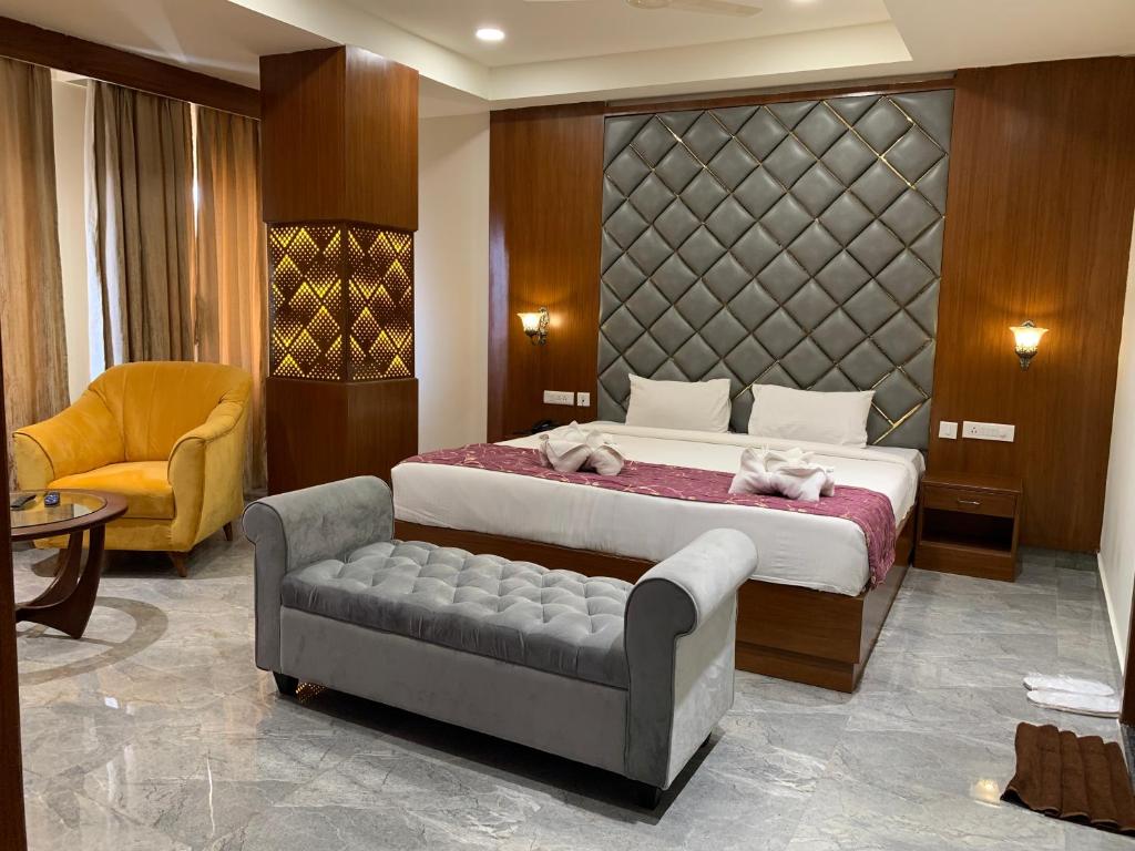 a bedroom with a bed and a couch and a chair at Hotel Hyderabad Grand in Shamshabad