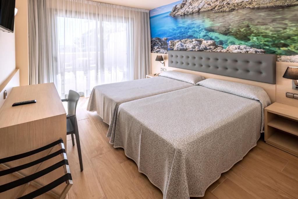 Un dormitorio con una cama, una mesa y un escritorio. en Tropic Park, en Malgrat de Mar
