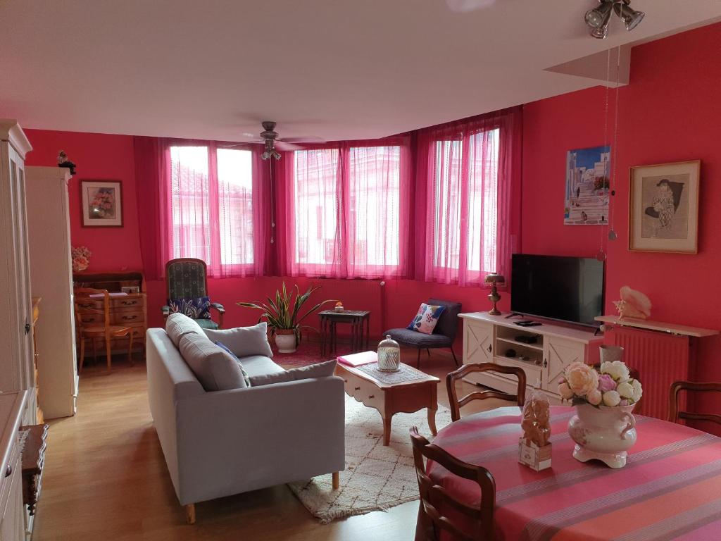 een woonkamer met rode muren en een bank en een tafel bij Appartement LA VIE EN ROSE in Périgueux