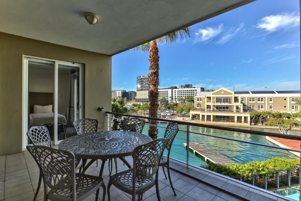 a balcony with a table and chairs and a view of a pool at Two Bedroom Apartment - fully furnished and design in Va Marina Residential in Cape Town