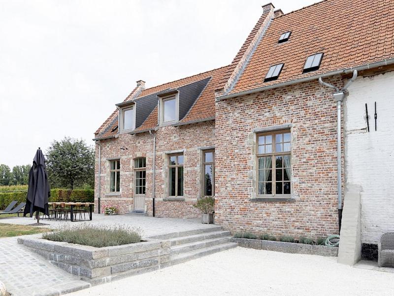 a brick building with a table and an umbrella at Huis Potaerde, stijlvol landhuis nabij Brussel voor 7 personen in Merchtem