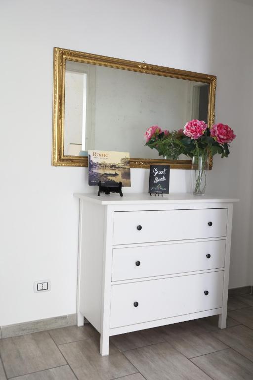 a white dresser with a mirror and flowers on it at Pietro's house in Rome