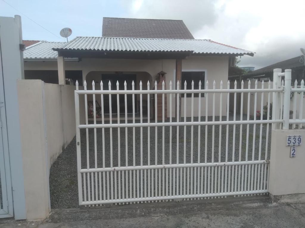 a white fence in front of a house at Casa pousada ,Gravata Navegantes in Navegantes