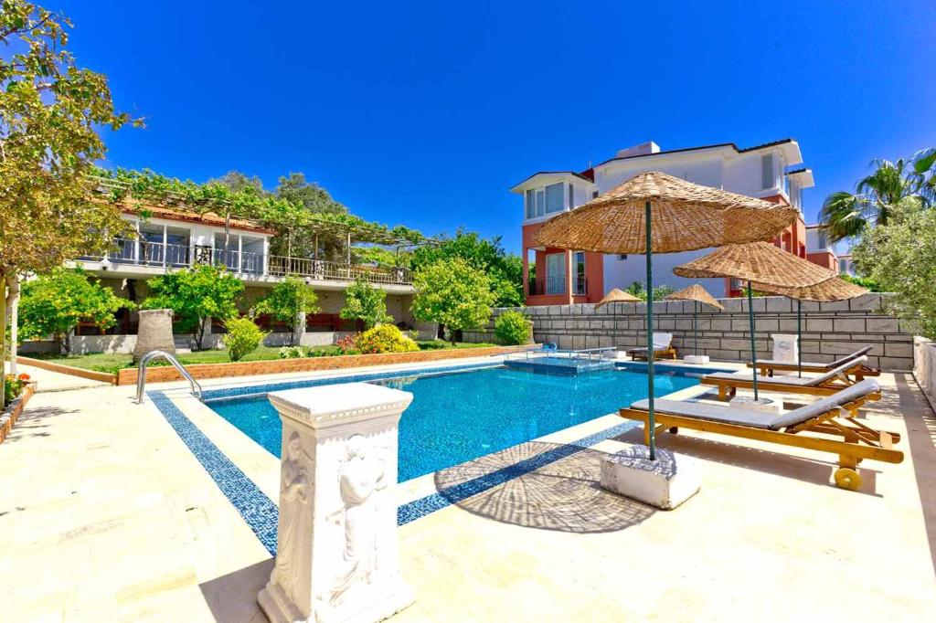 Patara Evleri في باتارا: مسبح فيه مظله ومنزل