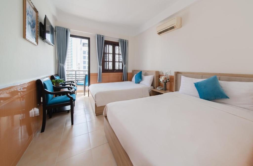 una camera d'albergo con due letti e una sedia di StarLight Nha Trang a Nha Trang