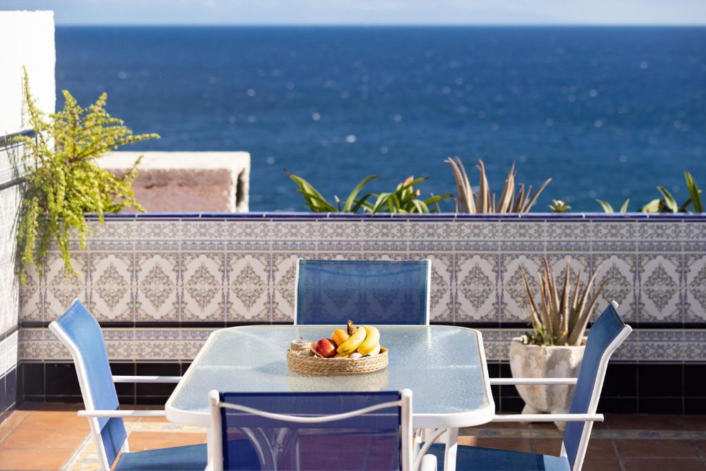a table and chairs with a bowl of fruit on a balcony at Home2Book Ocean Breeze Candelaria, Terrace & Pool in Candelaria