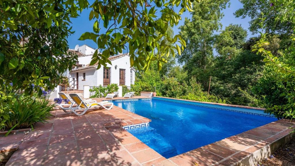 uma piscina com duas cadeiras e uma casa em Molino Maroto Alhaurín el Grande by Ruralidays em Alhaurín el Grande