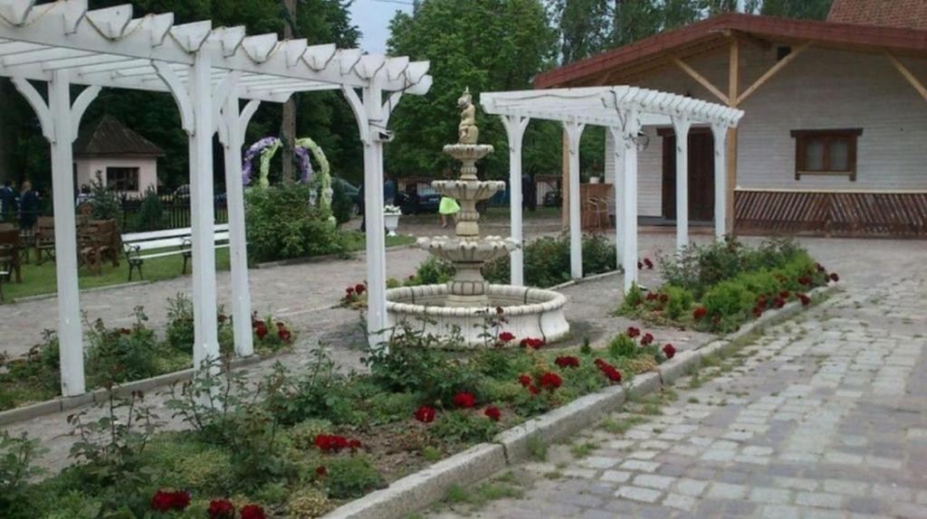 a garden with a fountain and a pavilion at Zajazd Eljan-Centrum Noclegowe in Olsztyn