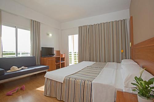 Habitación de hotel con cama grande y sofá en Hotel Alea en El Arenal