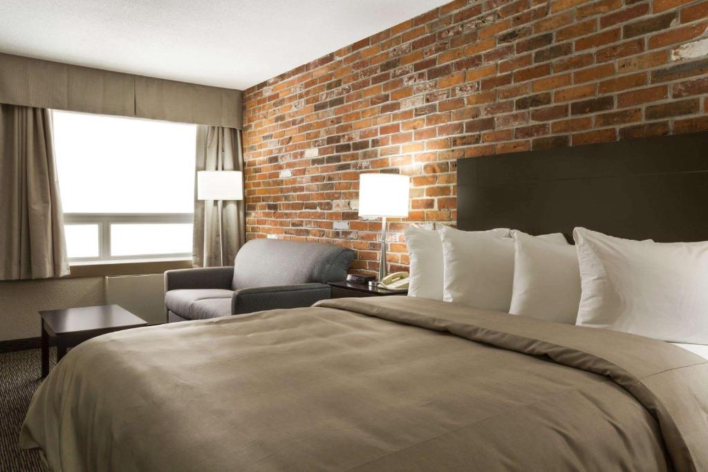 ein Hotelzimmer mit einem Bett und einer Ziegelwand in der Unterkunft Super 8 by Wyndham Timmins ON in Timmins