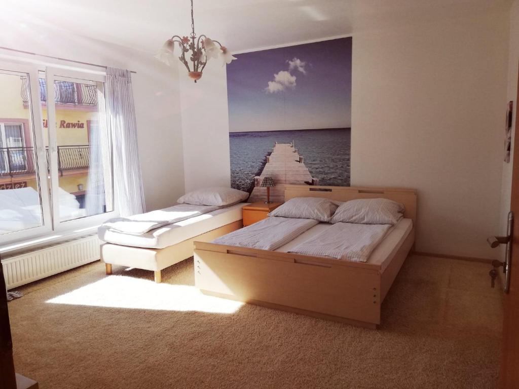 a bedroom with two beds and a painting of a pier at Pokoje Goscinne Bartek in Rewal