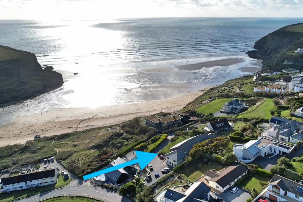an aerial view of a beach with a blue arrow at White Lodge - Coast Hideaways in Mawgan Porth
