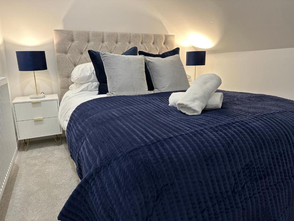 a blue bed with a blue comforter and two lamps at Stunning City Centre Apartments in Cardiff