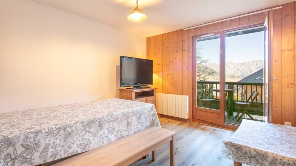 a bedroom with a bed and a tv and a window at Les Tetras- 60- Appart Renove - 8 pers in Saint-Sorlin-dʼArves