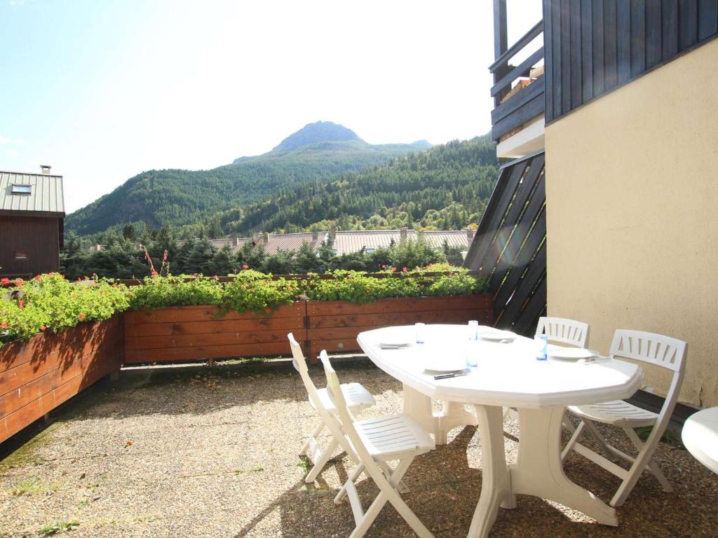 une table blanche et des chaises sur le côté d'un bâtiment dans l'établissement Studio familial à Serre-Chevalier, Chantemerle, avec terrasse et Wi-Fi en option, 4 pers - FR-1-330E-121, à Saint-Chaffrey