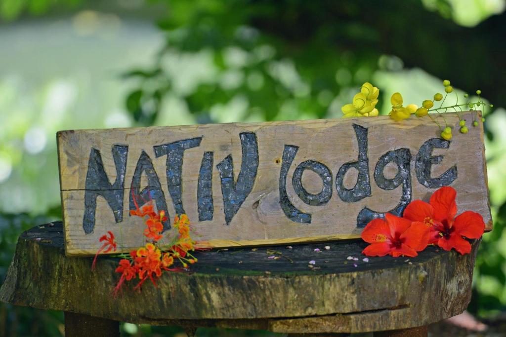 a wooden sign that says nanny lodge on a stump at Nativ Lodge and Spa in Mahébourg