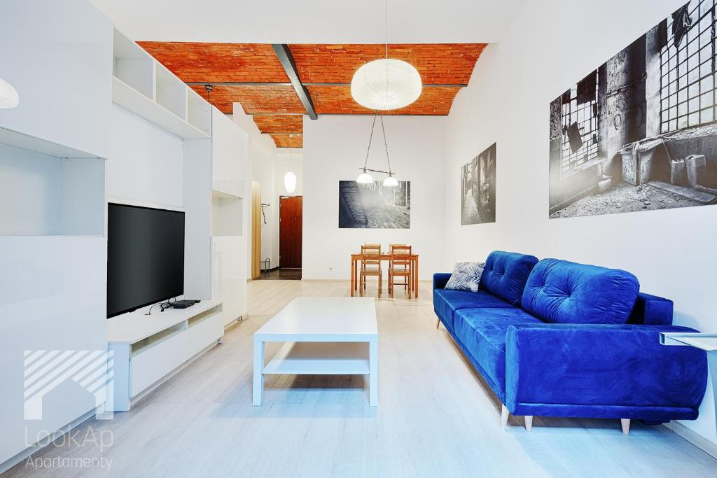 un soggiorno con divano blu e TV di Loft White by LookAp a Łódź