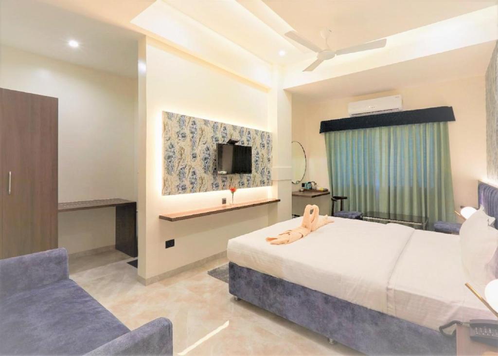 a bedroom with a bed and a couch and a tv at Hotel Rose Gold in Ahmadnagar