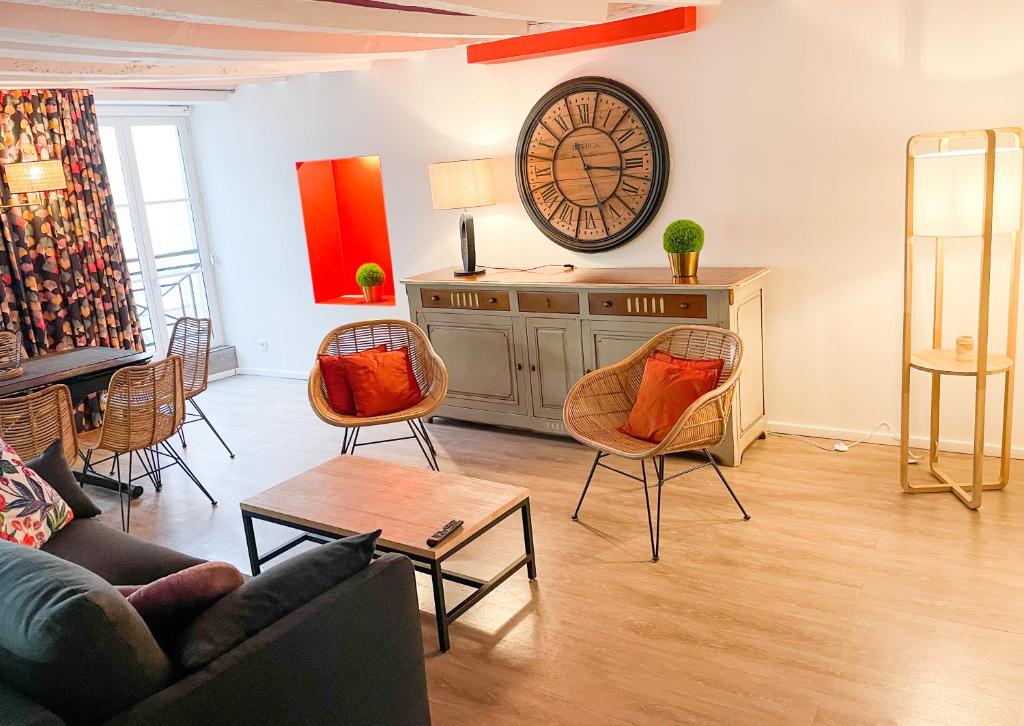 a living room with chairs and a clock on the wall at Bel appartement contemporain in Alençon