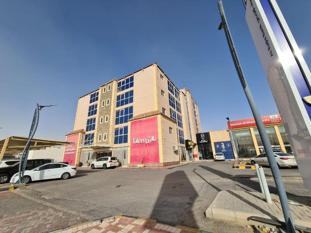 un gran edificio con coches estacionados en un estacionamiento en تـالـيـن الـهـفـوف, en Al Hofuf