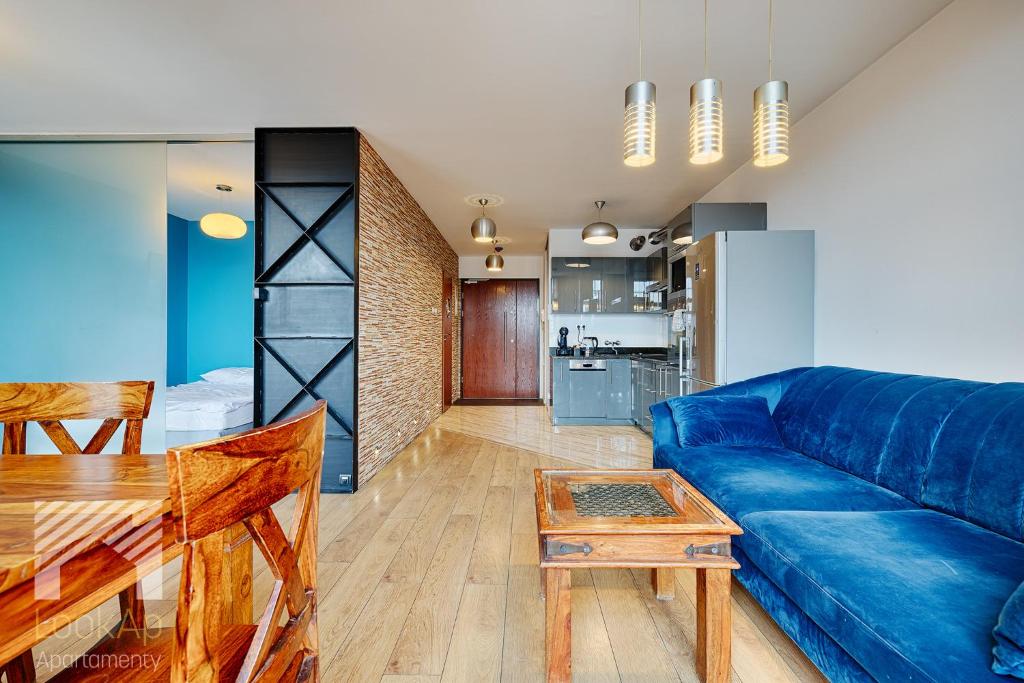 ein Wohnzimmer mit einem blauen Sofa und einem Tisch in der Unterkunft Loft Marmurowy by LookAp in Łódź
