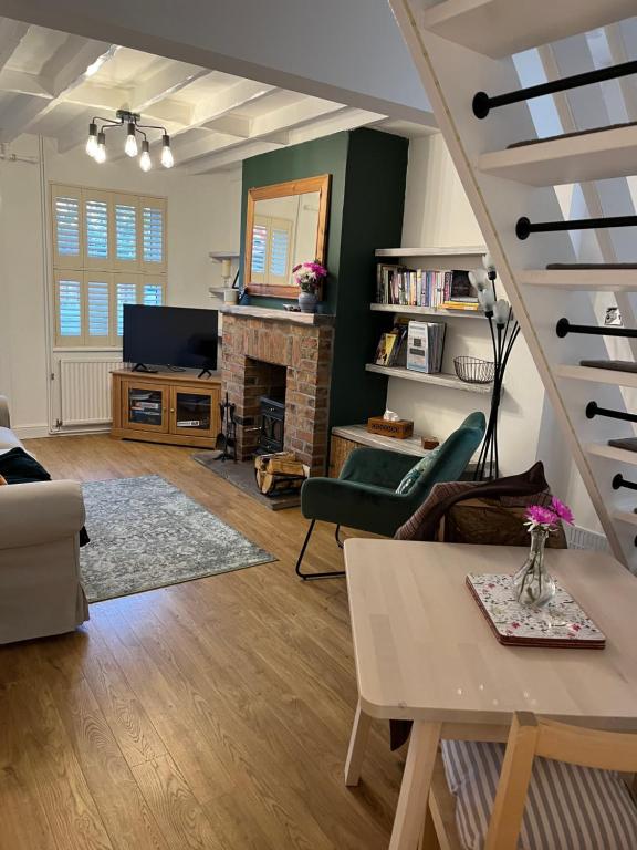 a living room with a staircase and a fireplace at Explorers Cottage, Yorkshire Wolds Character Home in Market Weighton