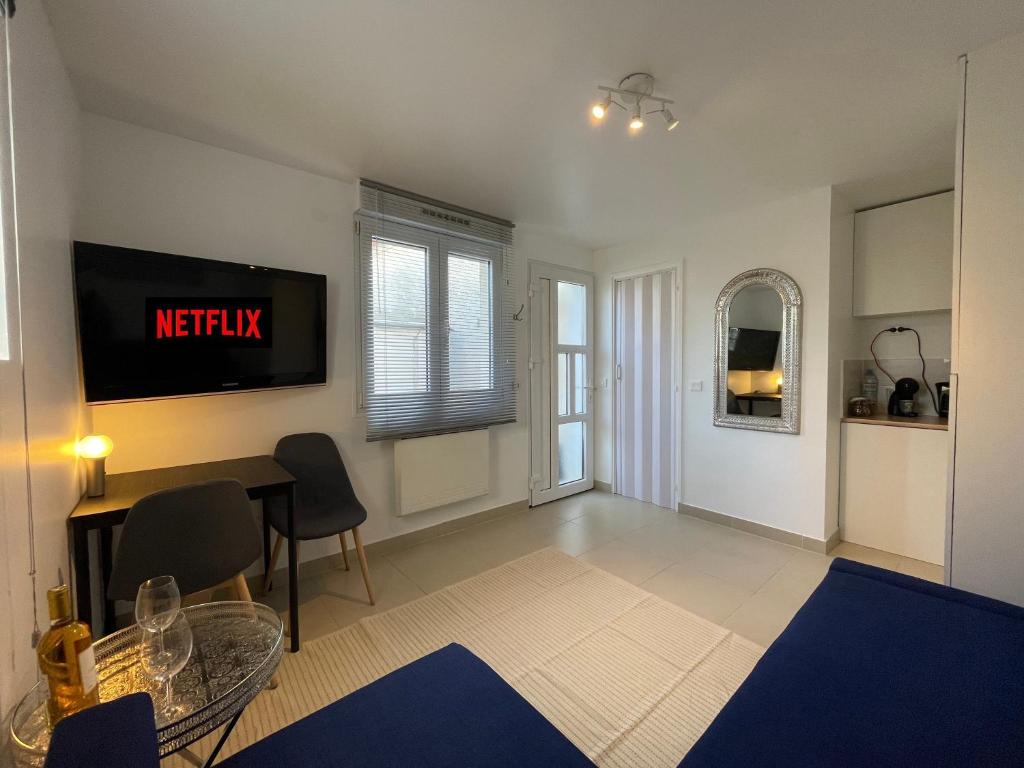a living room with a table and a tv on the wall at Studio D Cosy Parc des expositions Roissy CDG Airport in Vaujours
