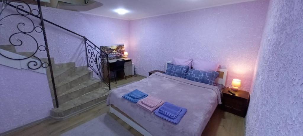 a bedroom with a bed with blue pillows and a staircase at Двухярусная квартира в центре Мукачева, улица Мира in Mukacheve
