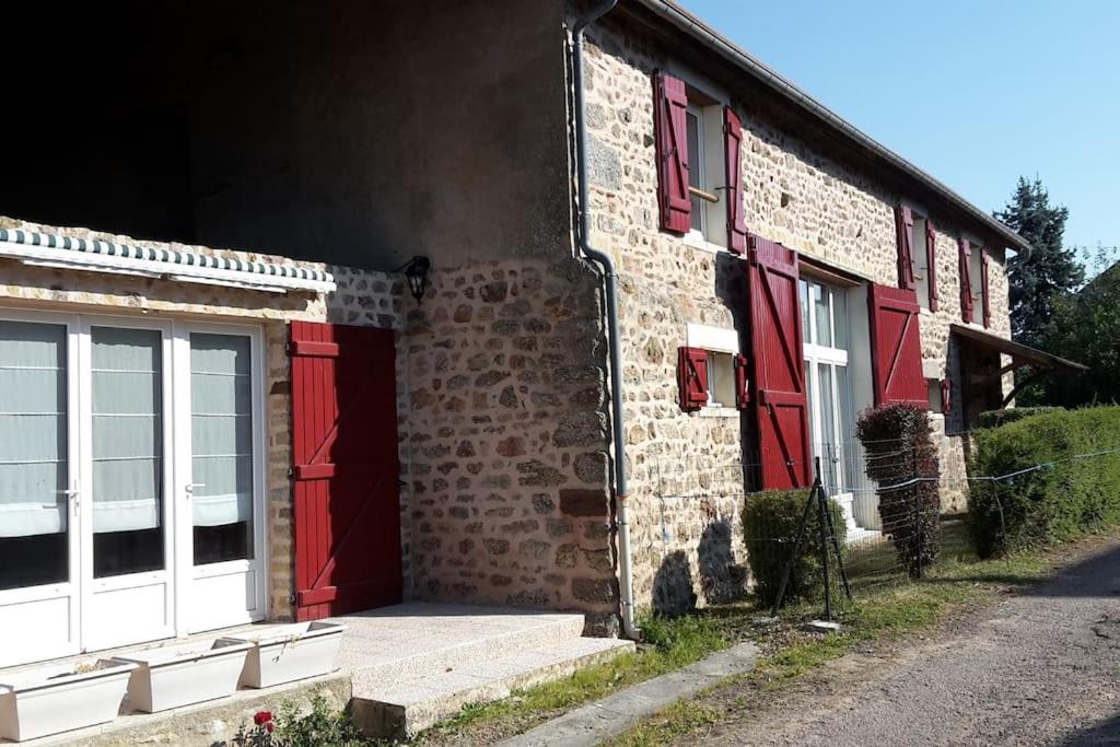 - un bâtiment en briques avec des portes et des fenêtres rouges dans l'établissement Grande Maison de charme, à Sainte-Magnance