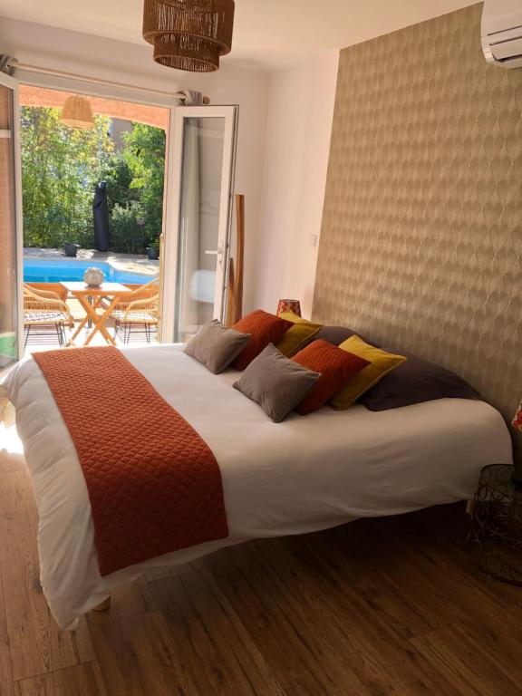 a large bed in a bedroom with a large window at Le Mas Victoria - Chambres d'hôtes avec table d'hôtes in Carcassonne