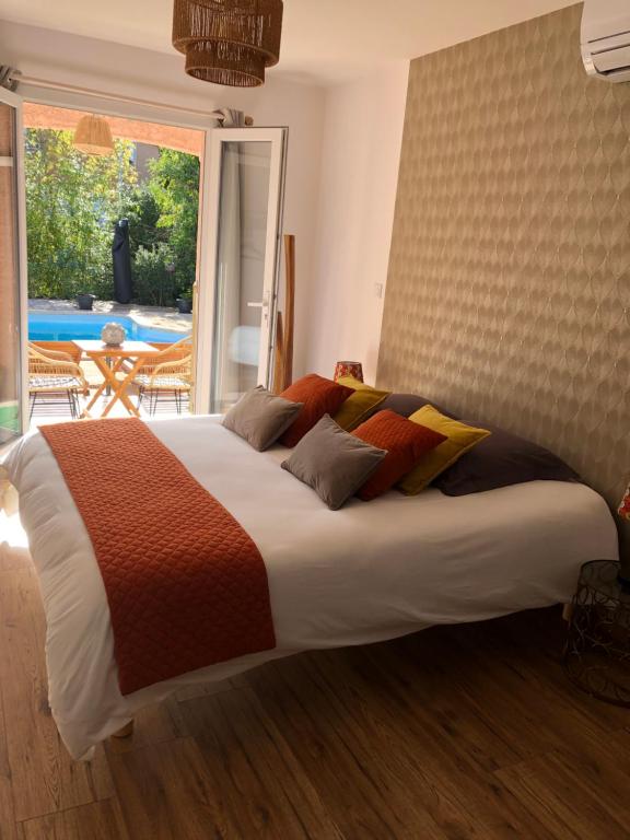 un grande letto in una camera da letto con una grande finestra di Le Mas Victoria - Chambres d'hôtes avec table d'hôtes a Carcassonne