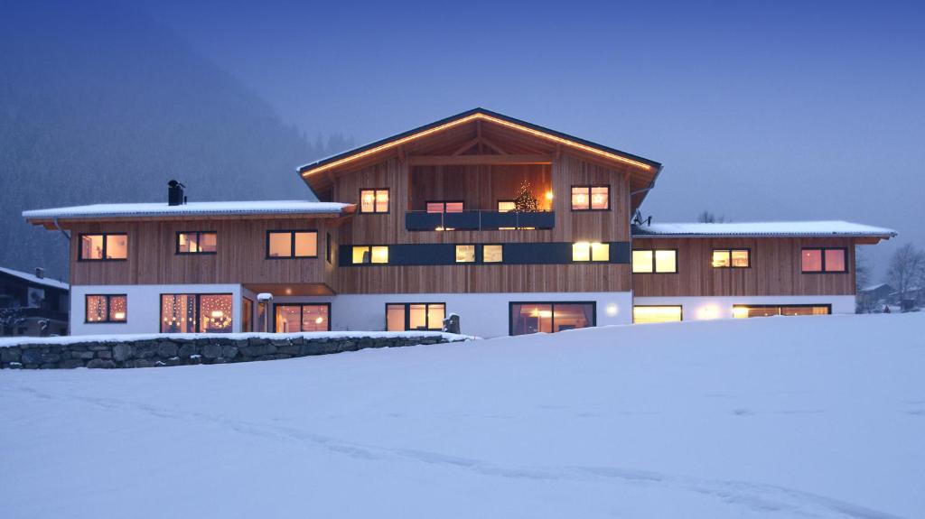 une grande maison dans la neige devant dans l'établissement Appartement Carola, à Sankt Gallenkirch