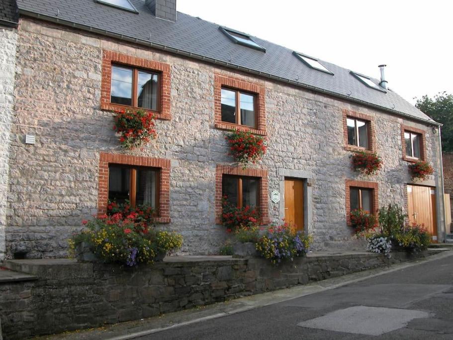 un edificio de ladrillo con flores en las ventanas en Maison de vacances familiale: le Petit Nid Mosan, en Dinant