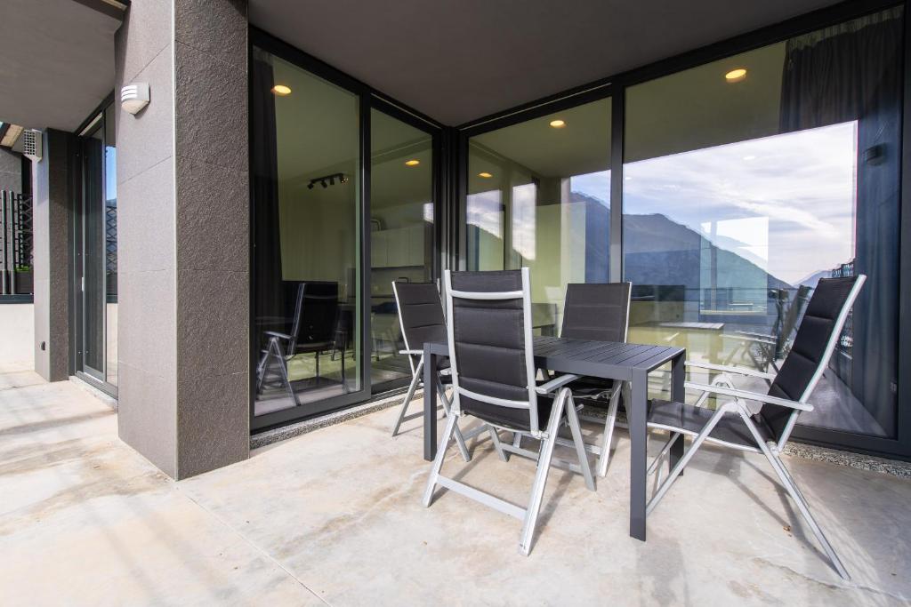 een zwarte tafel en stoelen op een balkon met ramen bij Art Vista Lake Como in Nesso