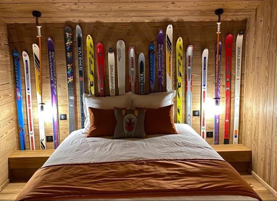 un montón de esquís alineados en una pared detrás de una cama en Chalet Jardin Alpin Valberg, en Péone