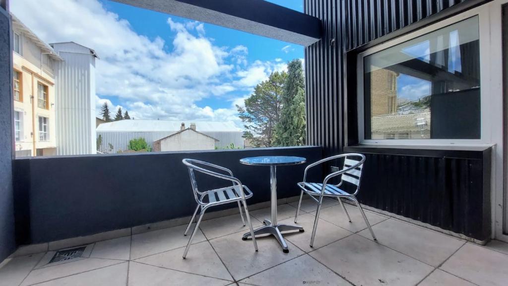 balcón con 2 sillas, mesa y ventana en Departamento con vista al lago y cerros en San Carlos de Bariloche