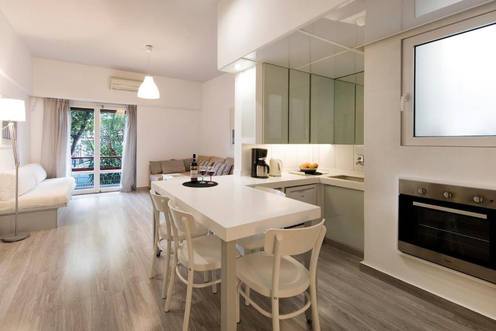 uma cozinha e sala de estar com uma mesa branca e cadeiras em Artistic apartment next to everything em Atenas