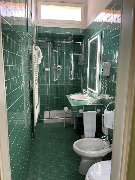a green tiled bathroom with a sink and a toilet at Hotel Roma in Bologna