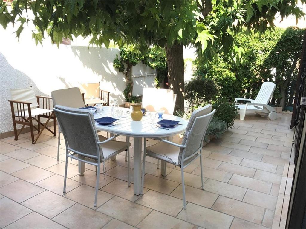 une table blanche et des chaises sur une terrasse dans l'établissement Charmante Villa T3 à Port Leucate, 5 couchages, proche plage, barbecue, garage - FR-1-81-98, à Port-Leucate