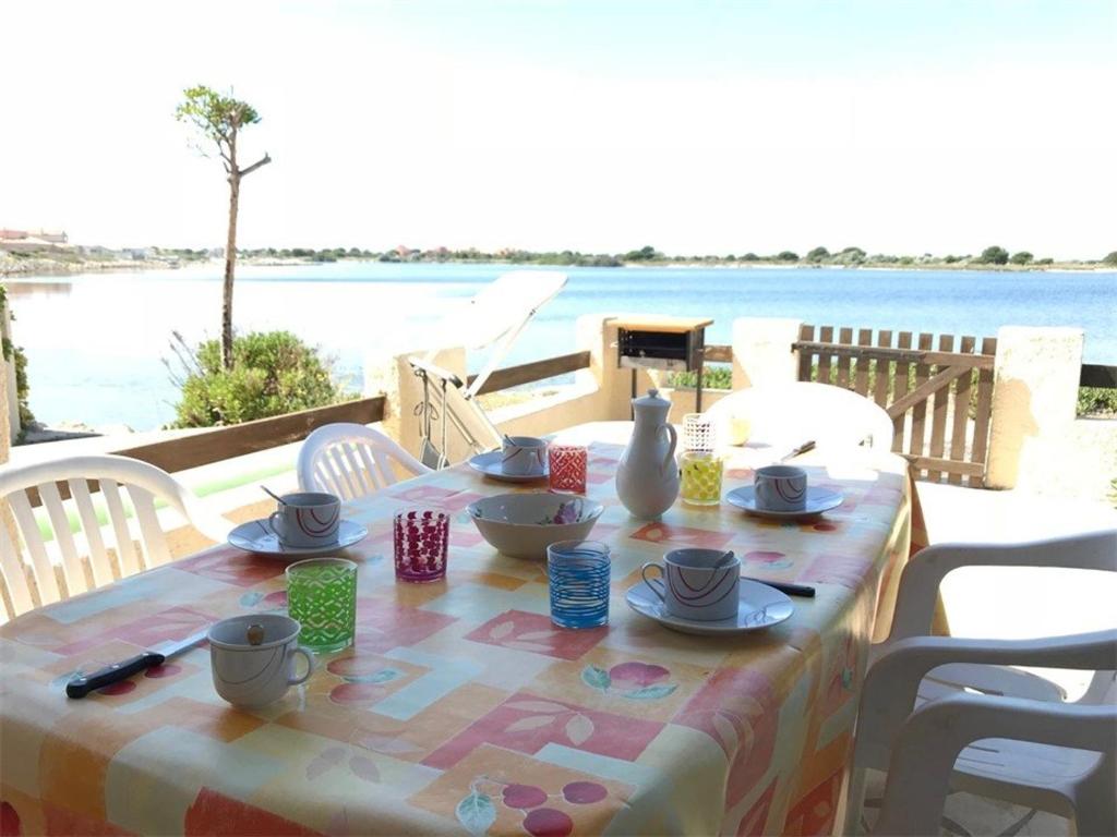 une table avec un tissu de table et une vue sur l'eau dans l'établissement Villa Face au Lac avec Terrasse et Barbecue - 3 Pièces + Mezzanine pour 6 Personnes - FR-1-81-96, à Port-Leucate