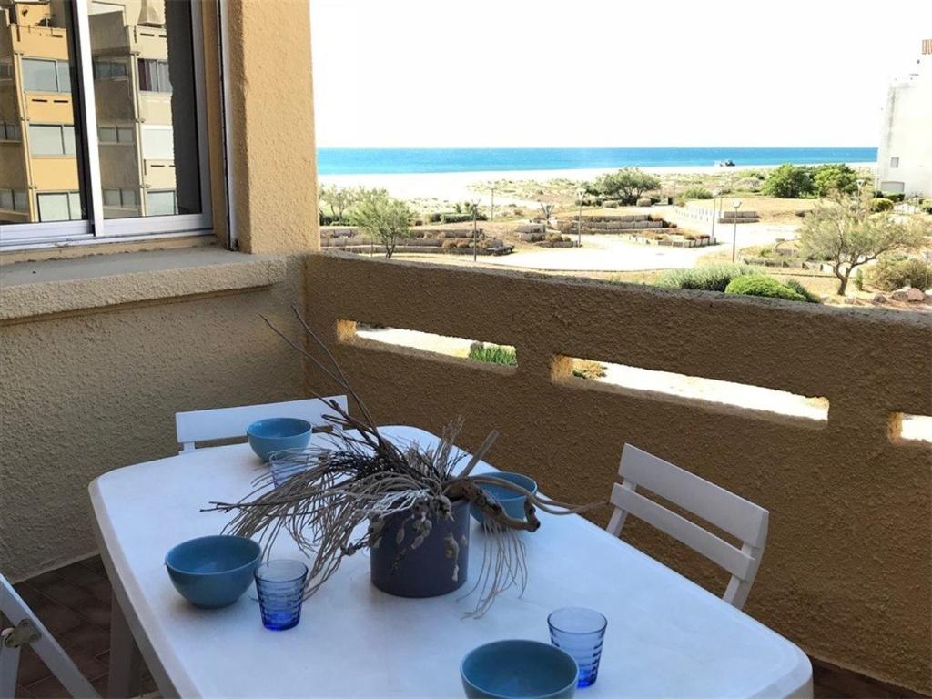 une table blanche avec des bols bleus et une plante sur elle dans l'établissement T2 à 50m de la plage, Parking privé, 4 pers - FR-1-81-117, à Port-Leucate